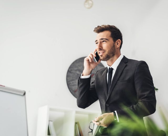 happy-young-businessman-talking-by-phone-in-office-2021-08-29-17-03-22-utc.jpg